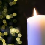 Large white wax candle in a black background.