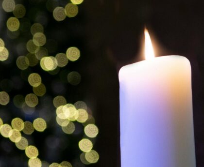 Large white wax candle in a black background.