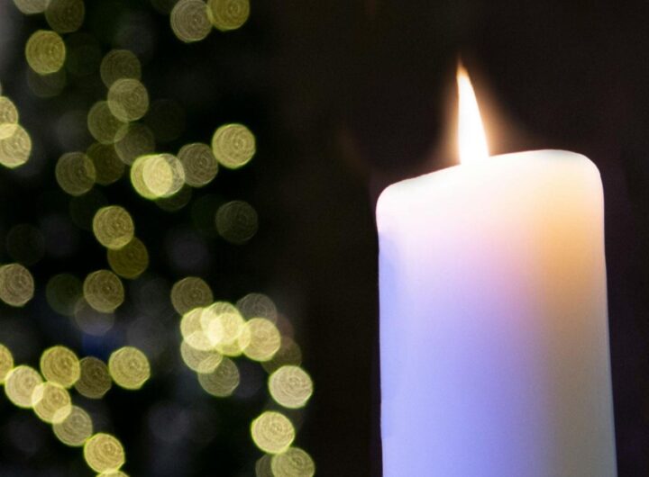 Large white wax candle in a black background.
